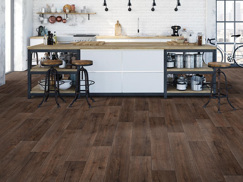 Dark brown Mohawk luxury vinyl plank flooring adds extreme style to a modern kitchen with a long island.