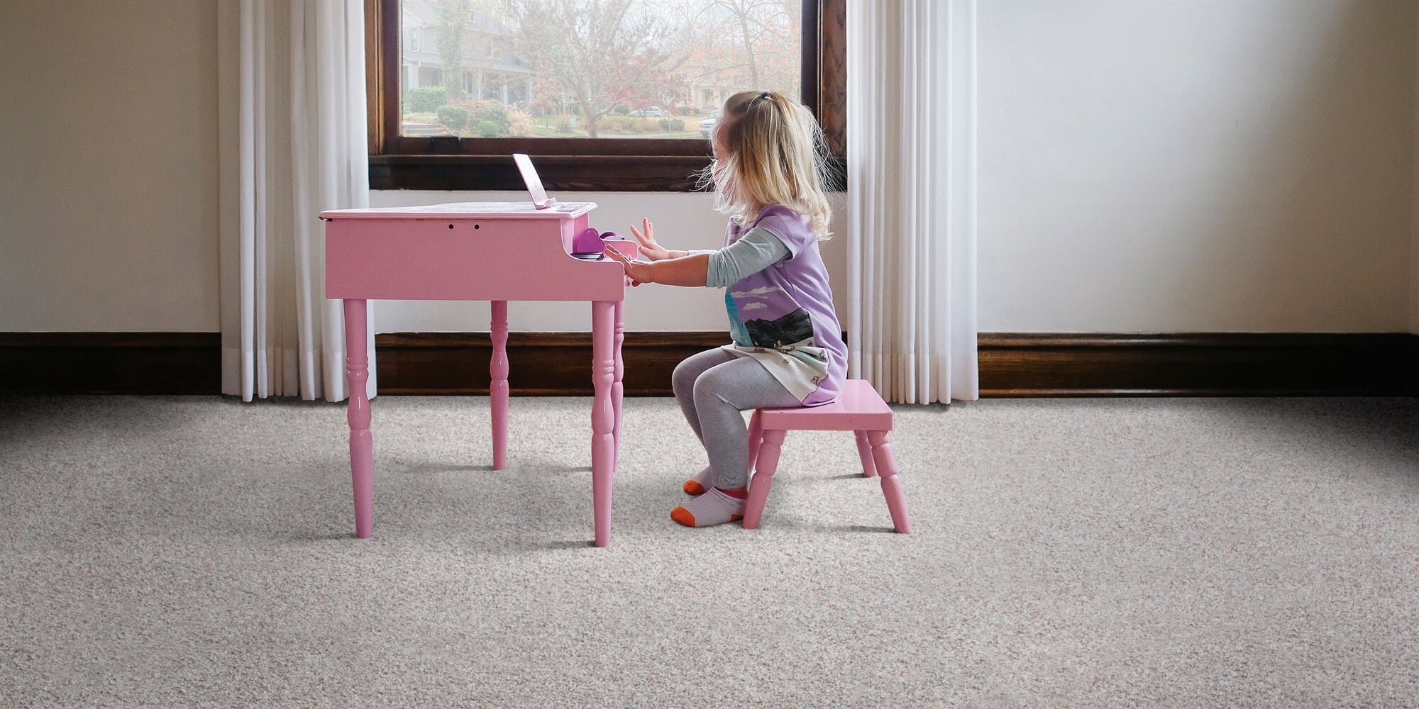 Girl playing toy piano in a room with soft carpet flooring